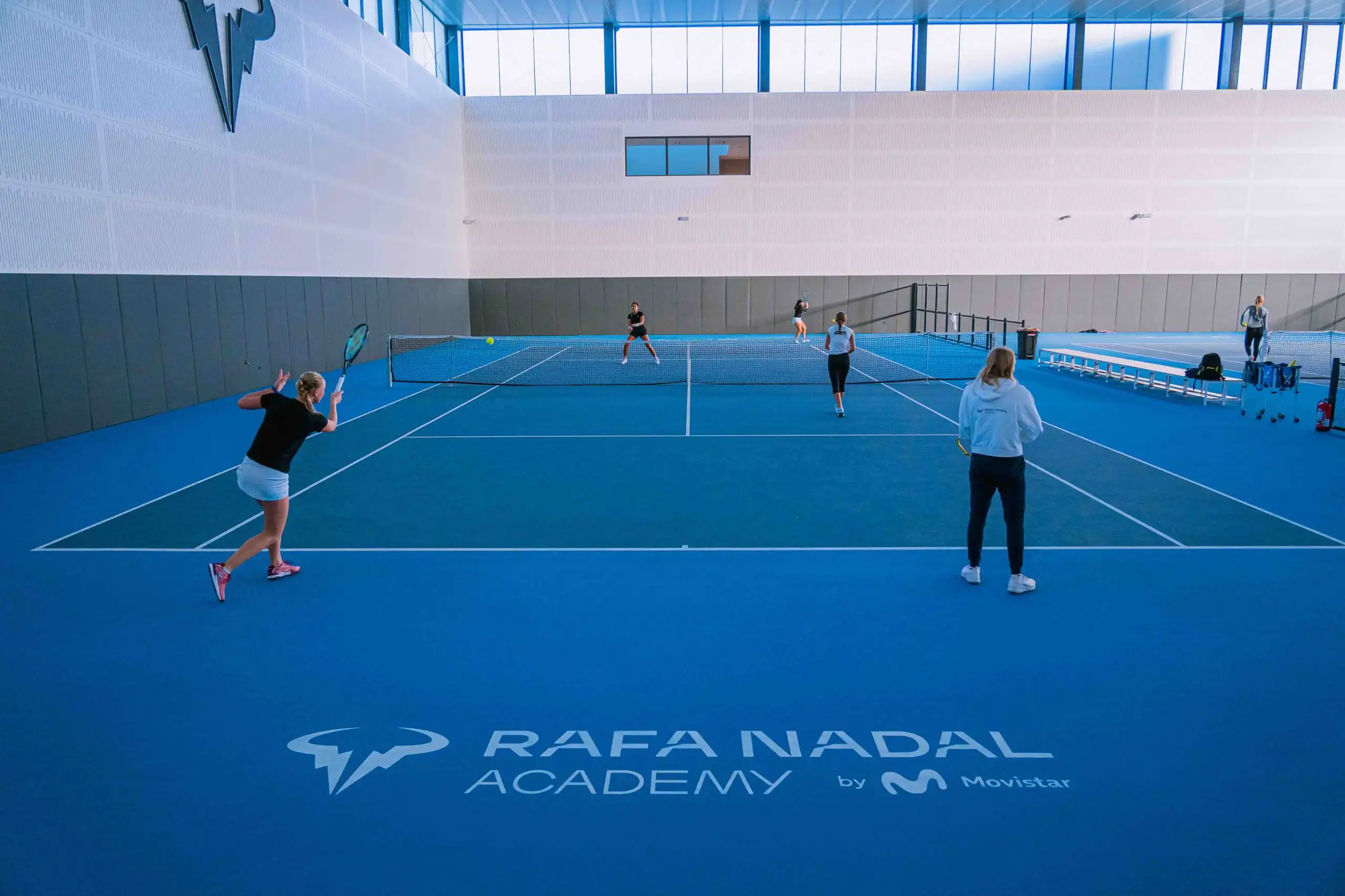 Players training on a Greenset blue hard court at the Rafa Nadal Academy indoor facility